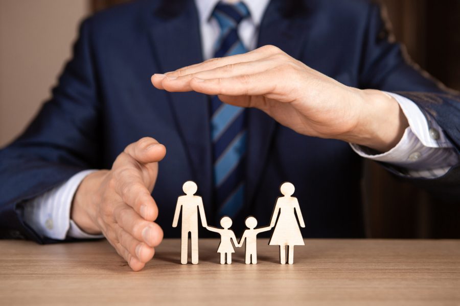 A man in a suit holds hands in the shape of a house over the family. Insurance concept.